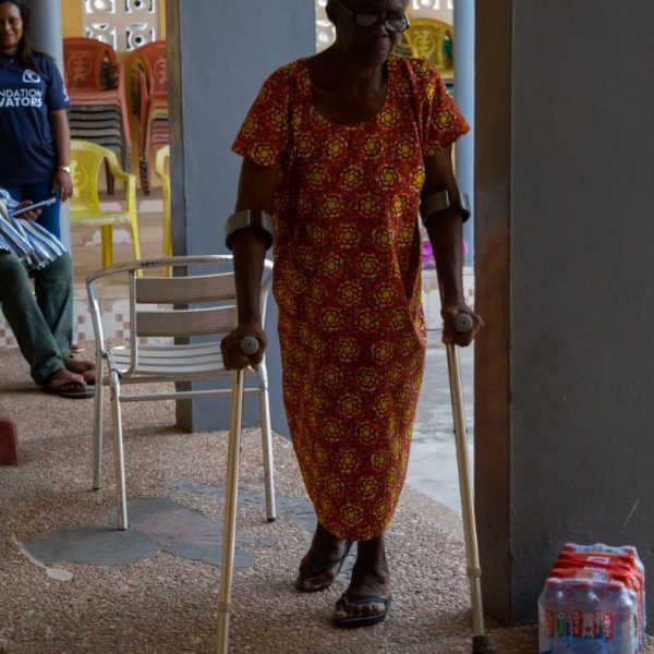 An elderly widow arriving at the community centre with a walking aid