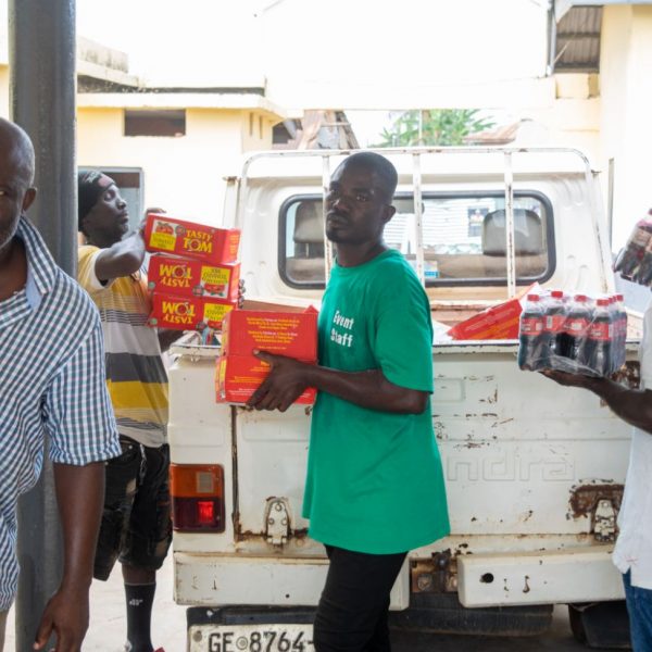 Community members helping to unload crates of drinks from the truck