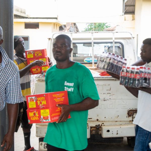 Volunteers and residents carrying cartons of tomato paste from the truck
