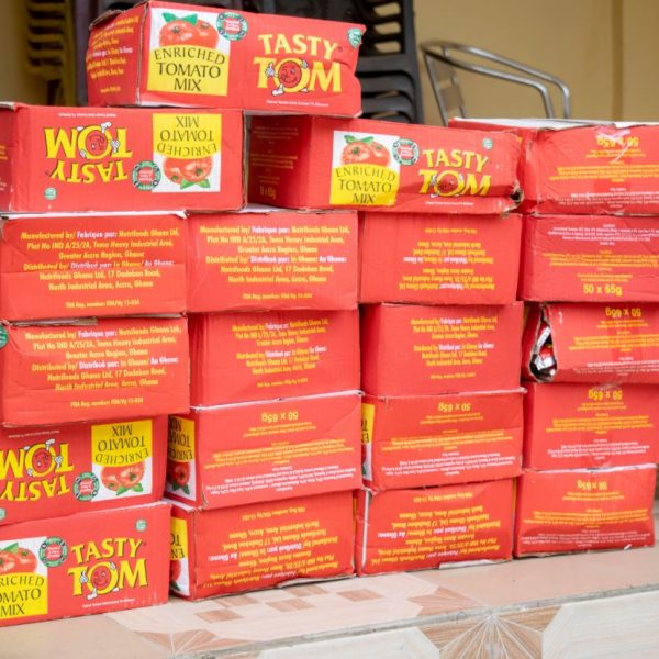 Cartons of tinned tomato paste stacked for the Widows in Need distribution