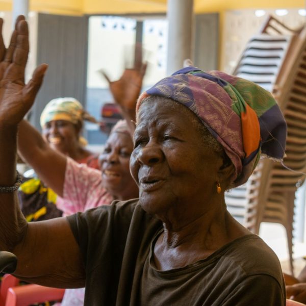 A beneficiary raises her hand to respond during the gathering