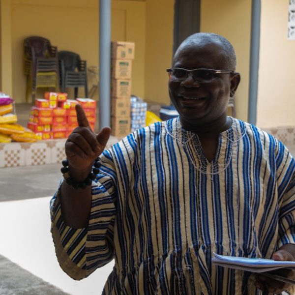 A community elder speaking in front of the stacked food supplies