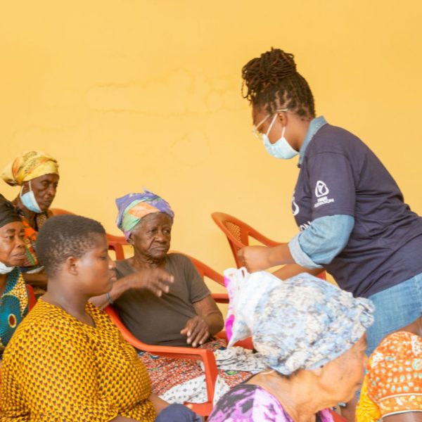 A volunteer handing a parcel to a seated beneficiary