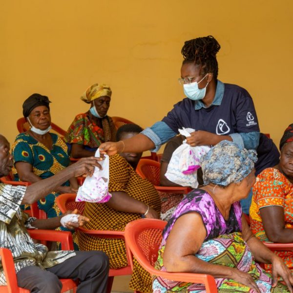 Volunteers distributing parcels along the rows of seated widows