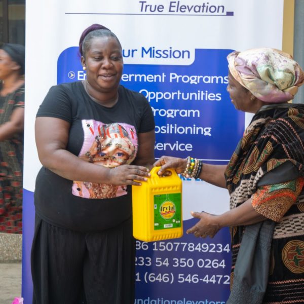 A volunteer presenting cooking oil to a beneficiary at the banner