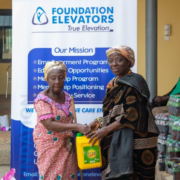 A beneficiary receiving cooking oil in front of the mission banner