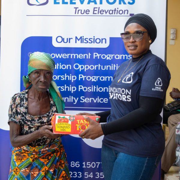 A beneficiary receiving a carton of tinned tomatoes from a volunteer