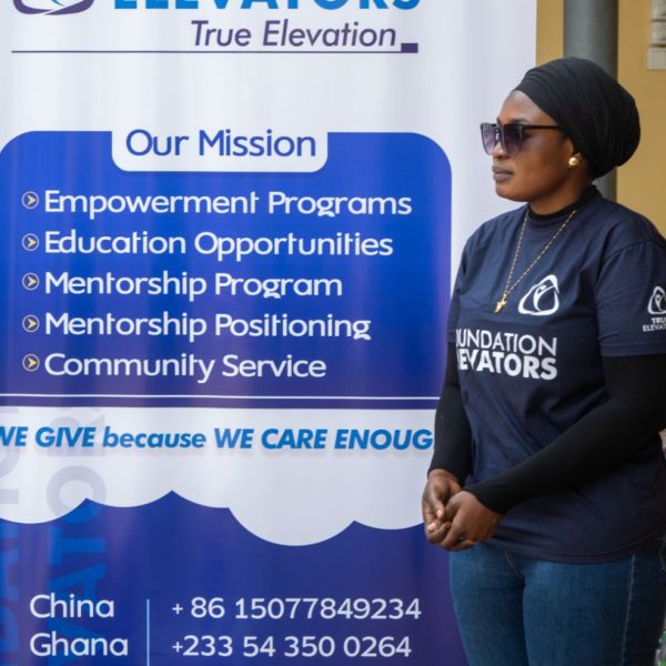 A volunteer in front of the banner listing the Foundation Elevators mission