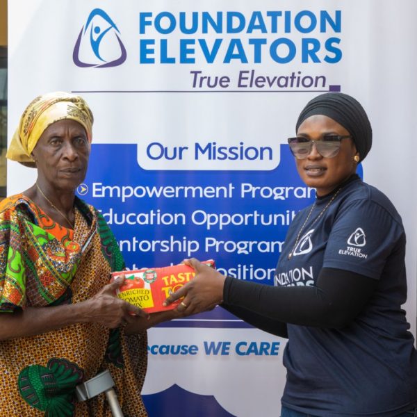 A Foundation Elevators volunteer handing supplies to a widow in front of the mission banner